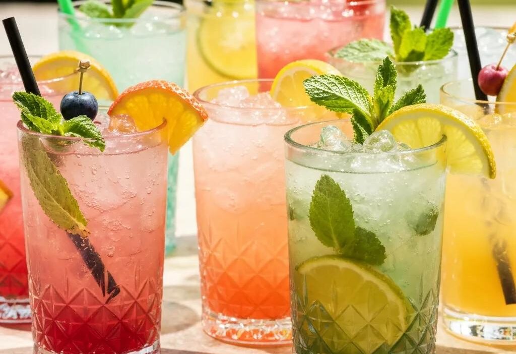 Colorful tropical cocktails with fresh fruits and herbs in a sunny outdoor setting