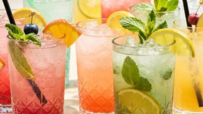 Colorful tropical cocktails with fresh fruits and herbs in a sunny outdoor setting